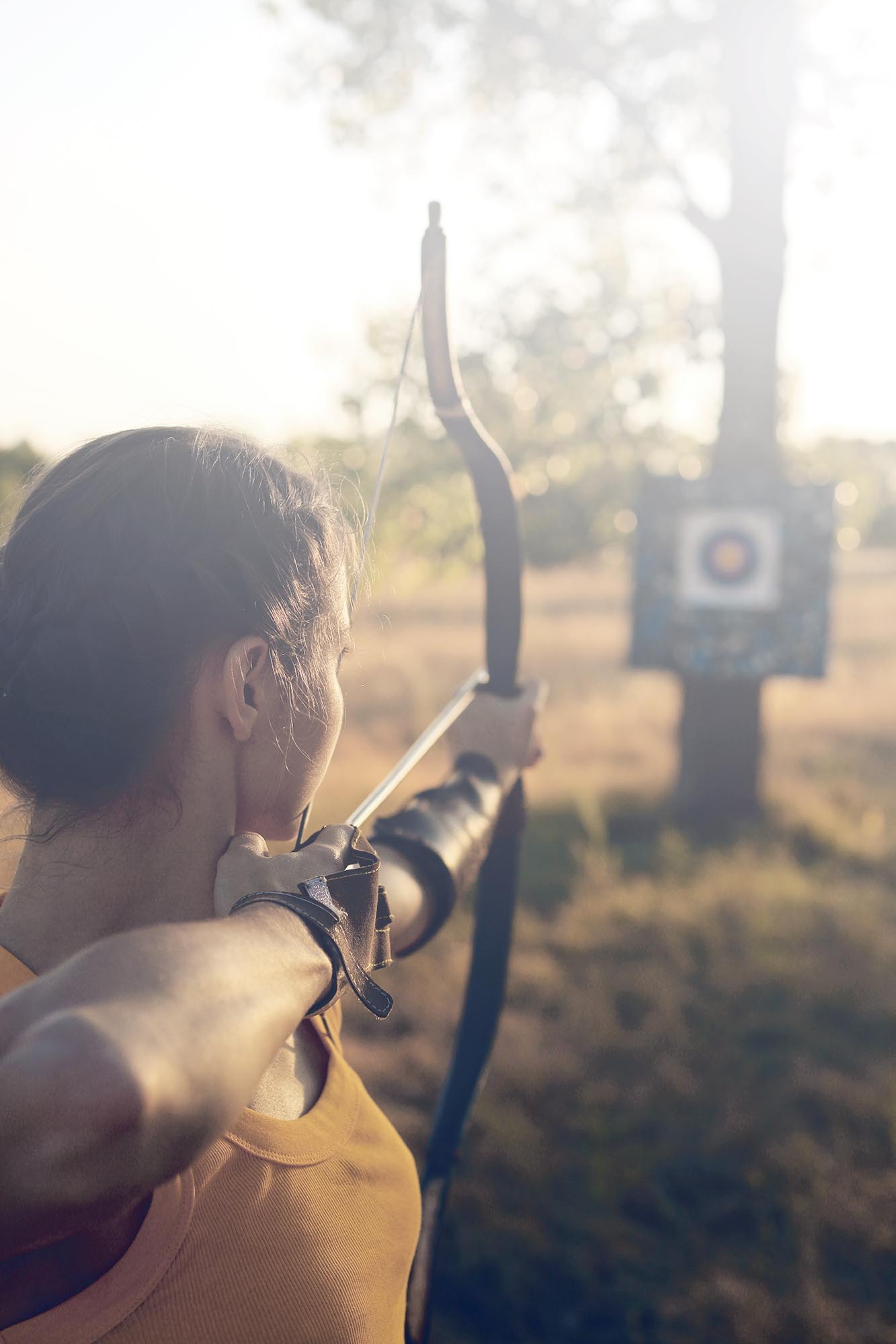 Female archer in the field at sunset